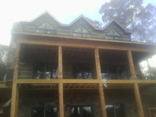 Dormers and porch framing on a large log home under construction — Roof Coating work by our crew in Tennessee