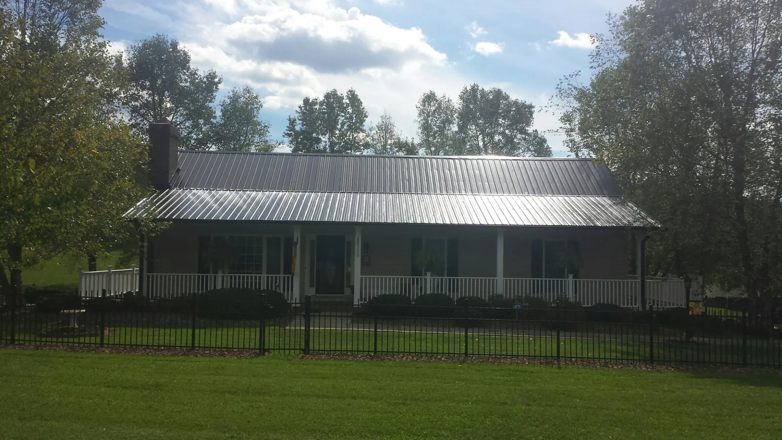 Gray metal roof on a brick ranch with a full width front porch — Gutter Guard Installation work by our crew in Tennessee