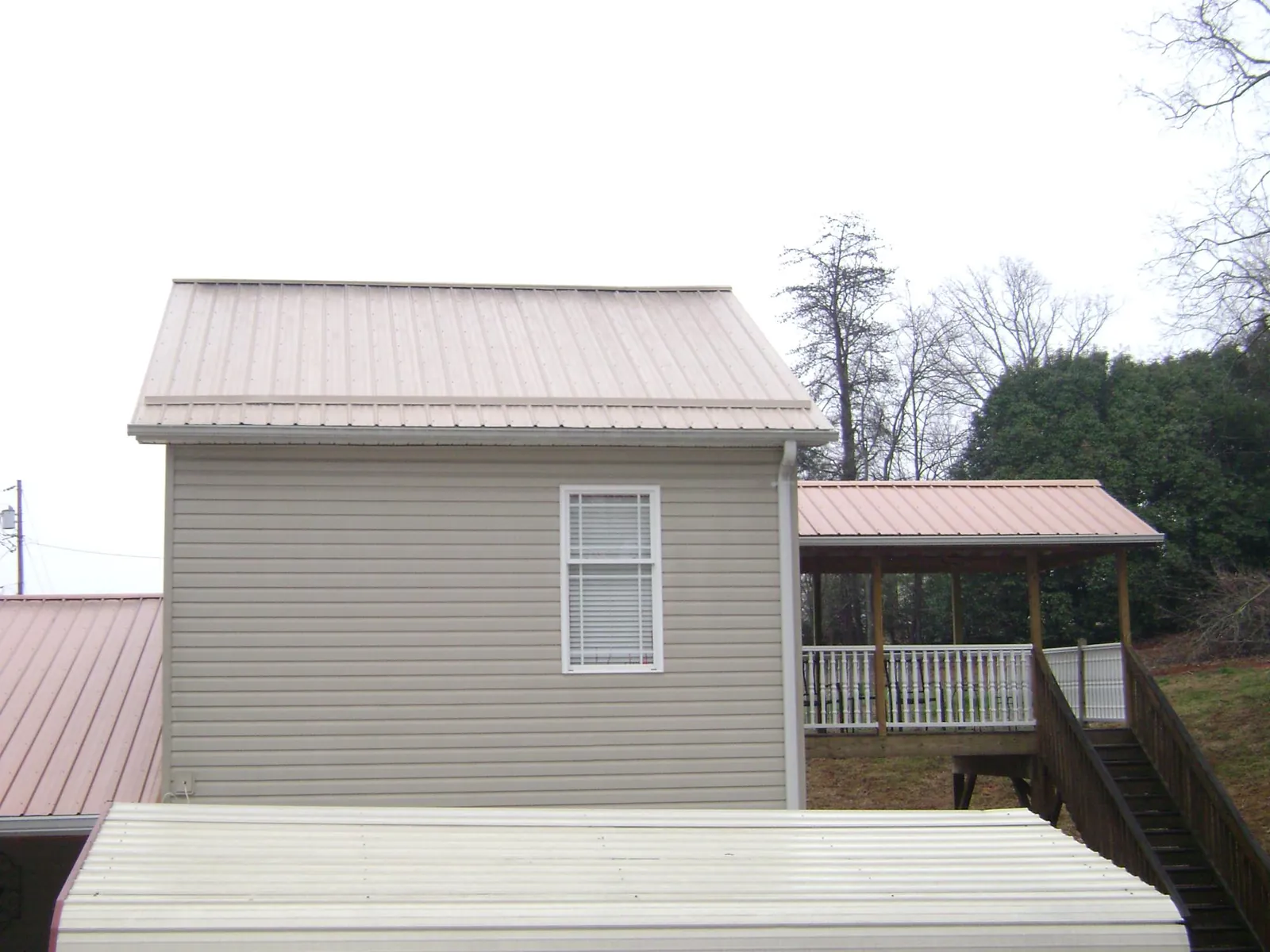 Tan metal roofs on a two story addition and attached porch, from a Roof Replacement job in Tennessee