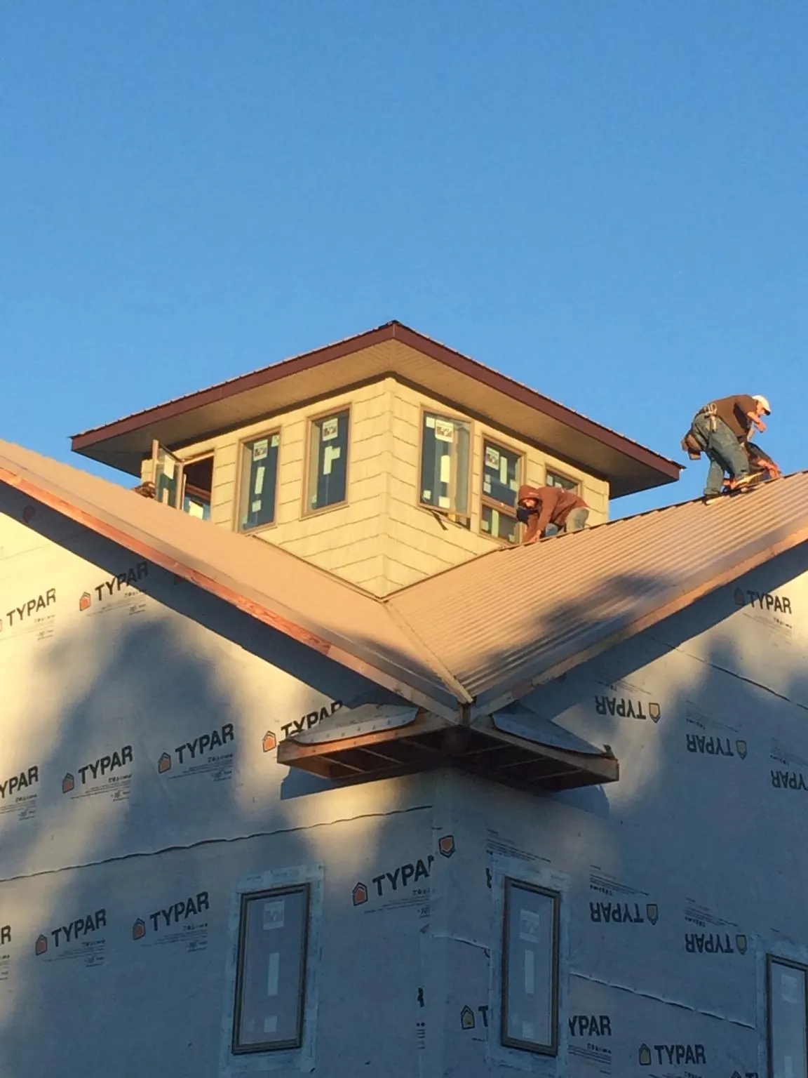 Roofers working around a rooftop cupola on a new metal roof at sunset — Roof Waterproofing in Tennessee by Roofing Brothers